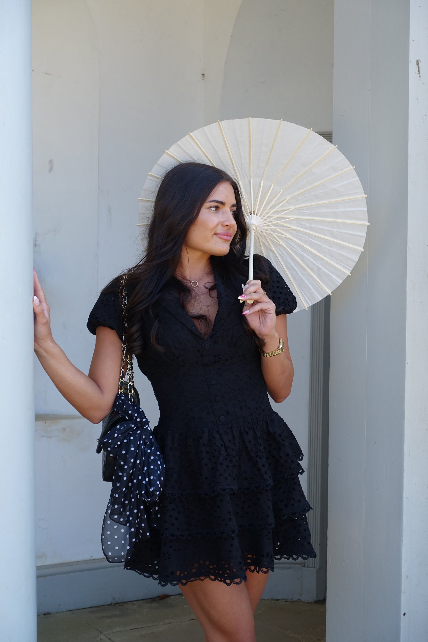 Woman holding a white parasol against a neutral background