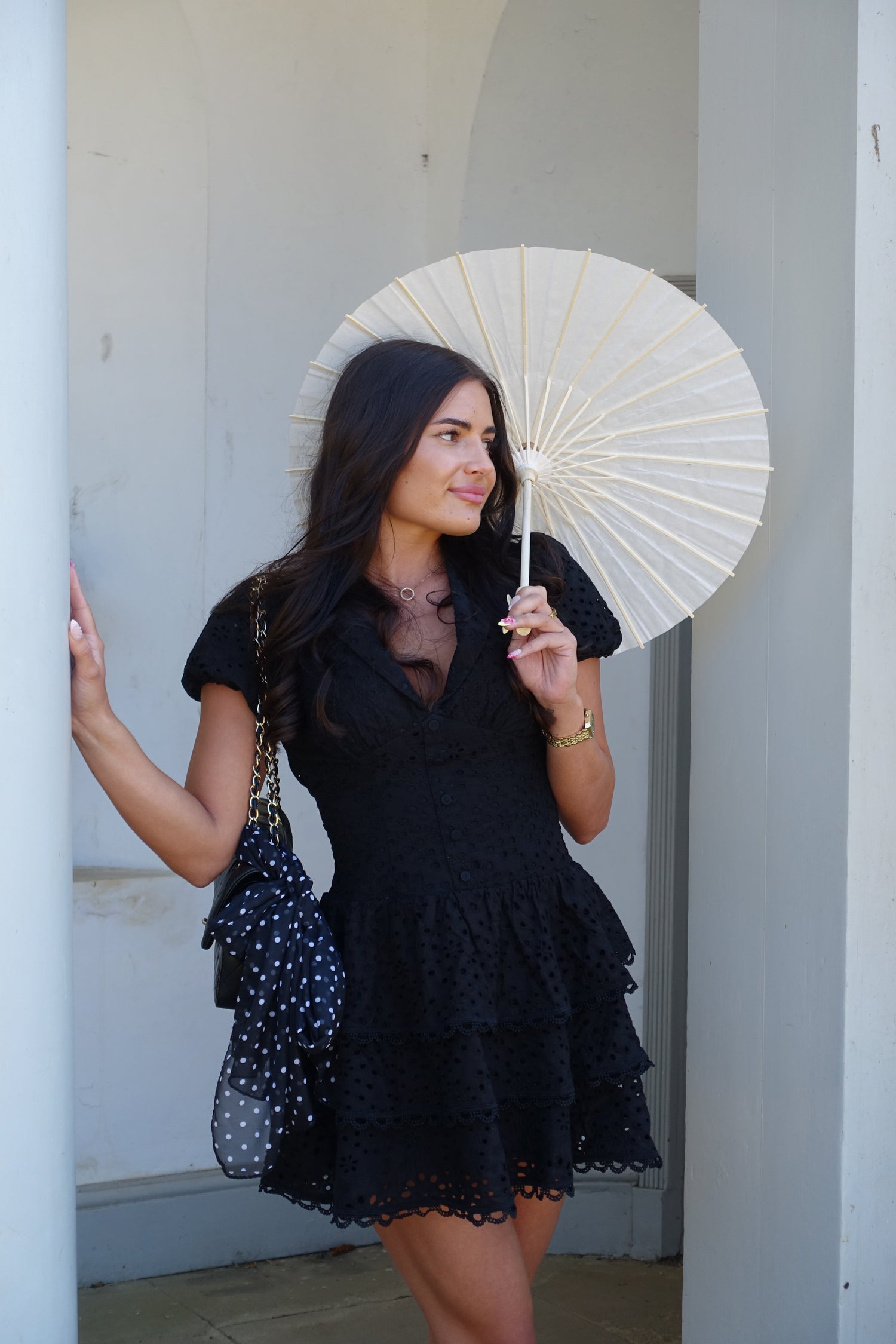 Woman holding a white parasol against a neutral background